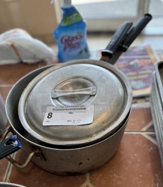 Assorted saucepans with lids, used condition, includes auction label indicating item number 8 and bid number 2.
