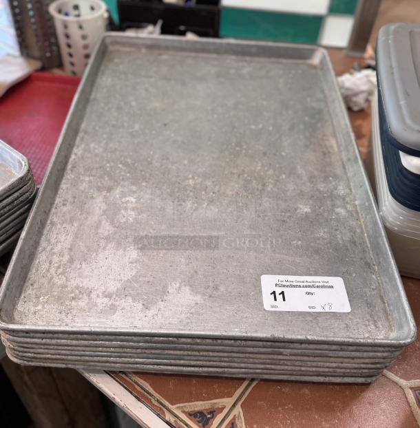 Large sheet pans, 8-count, used condition. Auction tag visible; indicates quantity and auction info.