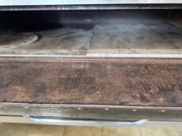 Bakers Pride pizza oven interior with visible wear on cooking surface and handle, suitable for commercial use.