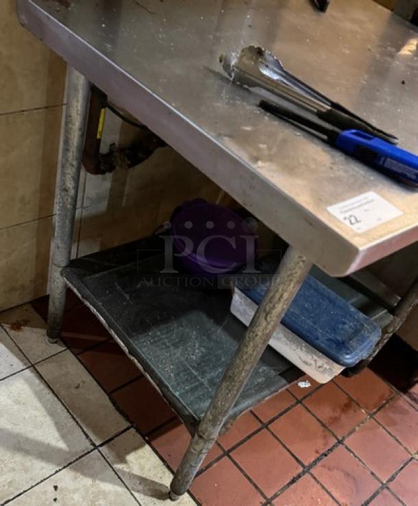 Stainless steel work table with lower shelf. Some signs of wear. Includes utensil and storage boxes.