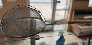 Double mesh strainer with wooden handle, metal frame, and tag labeled "28." Excellent condition, ideal for fine straining.