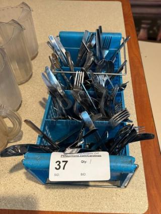 Assorted flatware in blue dishwasher rack, includes various forks, knives, and spoons. Auction tag marked "37".