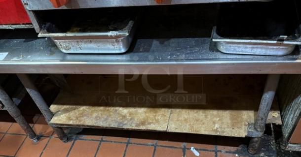 Metal equipment stand with two shelves, visible wear, used condition. Ideal for kitchen or catering setups.