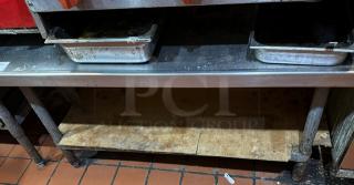 Metal equipment stand with two shelves, visible wear, used condition. Ideal for kitchen or catering setups.