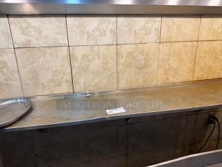 72" stainless steel wall shelf with a slight patina, mounted against beige tile wall. Includes auction tag number 43.