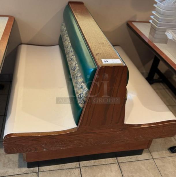 Dining room double booth with finished ends, featuring wood trim, green and patterned backrest, and cream seating. Auction tag visible.