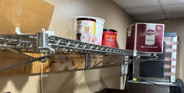 Wire wall shelving with metal mesh design, installed on a wooden board. Items stored include coffee cans and a cheese box.