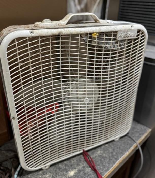 Vintage box fan with 5 speeds, white grille, visible logo on top corner, light wear and dust on surface.