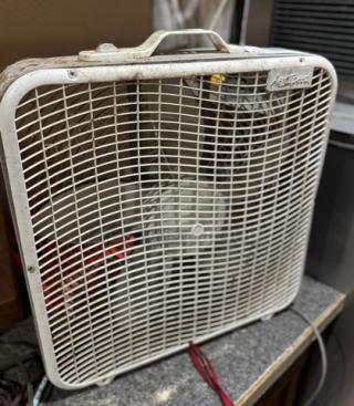 Vintage box fan with 5 speeds, white grille, visible logo on top corner, light wear and dust on surface.