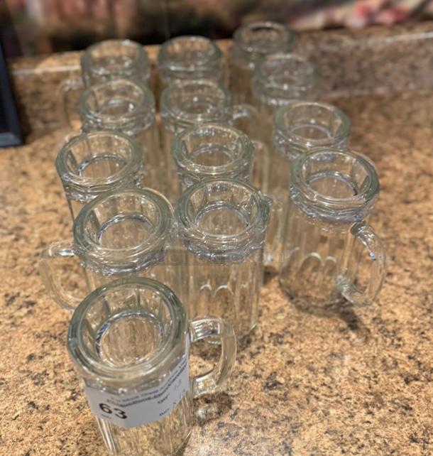 Set of 13 glass beer mugs in good condition, each with a handle. Auction label "63" visible.