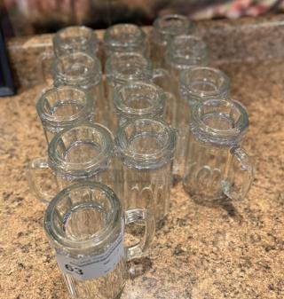 Set of 13 glass beer mugs in good condition, each with a handle. Auction label "63" visible.