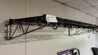 Wire wall shelving unit with metal frame and hooks, marked with sticker "72," mounted on wall, moderate wear.