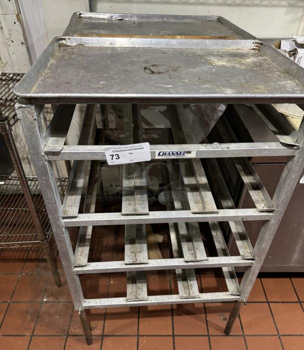 Stainless steel 303 can rack with multiple shelves. Visible wear and rust. Label indicates "Channel" brand. Auction lot tag "73".