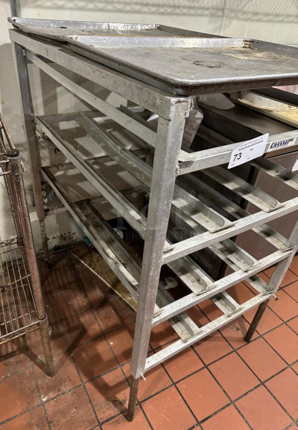 Metal 303 can rack with multiple shelves, visibly worn with surface rust, ideal for commercial kitchen storage. Auction tag 73 attached.