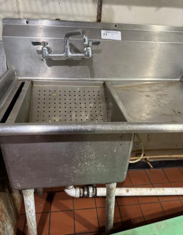 Stainless steel 1 compartment sink with drain board, built-in strainer, and faucet. Numbered tag on backsplash. Used condition.
