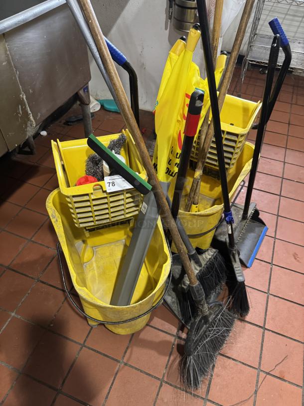 Assorted cleaning equipment includes yellow buckets, brooms, and mops in used condition; auction tag visible.