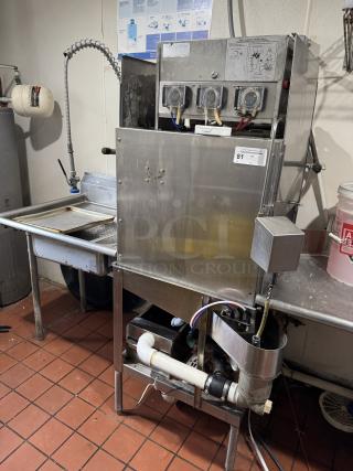 Commercial dishwasher with three Diversey detergent buckets, stainless steel body, multiple controls, and visible piping, in used condition.