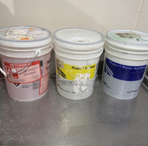 Three Diversey chemical buckets: red detergent, yellow sanitizer, blue rinse additive. Labels indicate function and capacity.