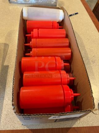 16 red and white squeeze type condiment bottles in a cardboard box, shown in used condition.