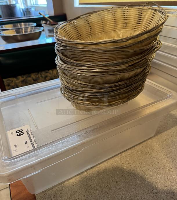 Large acrylic container with lid and ten wicker bread baskets. Container marked "89." Suitable for storage or display.