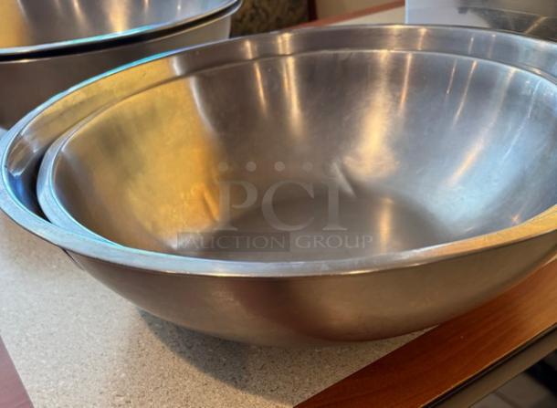 Two stainless steel mixing bowls in excellent condition, nested. Smooth finish, ideal for kitchen use. Perfect for auctions.