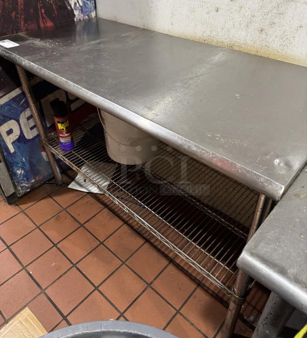 Stainless work table with wire undershelf, used condition. Steel construction with scuffs. Includes undershelf for storage.