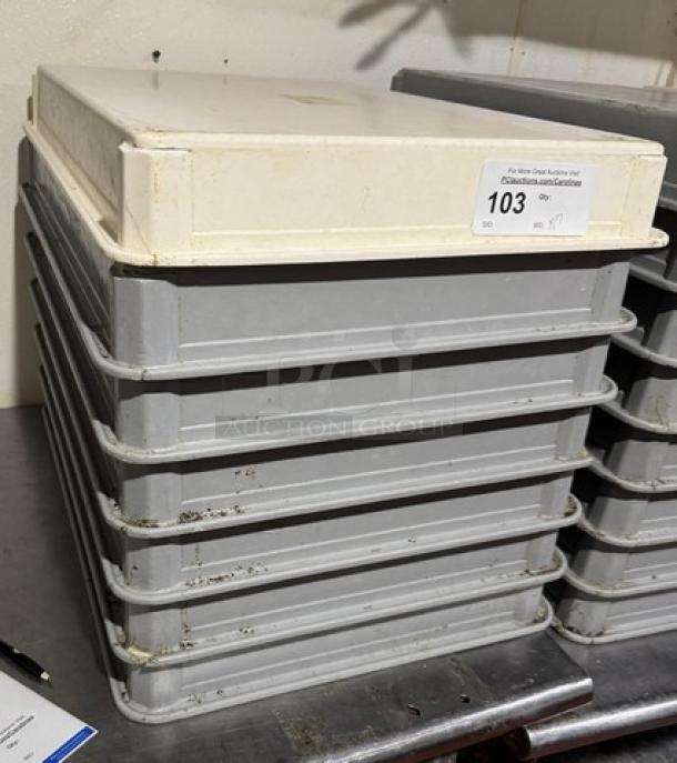 "Stack of seven gray dough pans with a white lid, showing signs of wear. Lot number 103 tag visible on top pan."