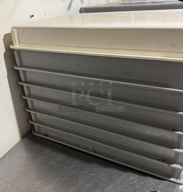 Stack of 7 dough pans, metal construction, used condition with visible wear, ideal for baking and storage.