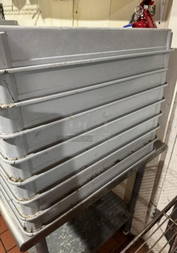 Stack of 8 industrial dough pans, well-used condition, gray, with visible wear marks, ideal for bakery operations.