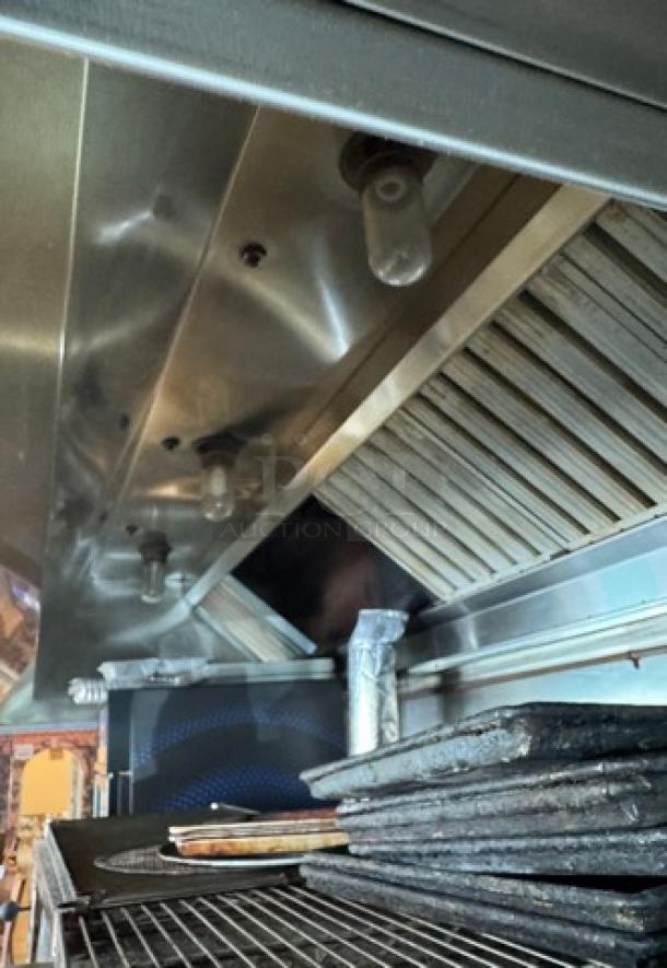Mannbuilt stainless hood showing integrated lighting, filters, and venting system. Appears in used condition. Ideal for kitchen installation.