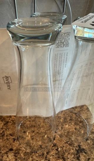 Two clear beer glasses, tall with a wide rim, in excellent condition. Set against a countertop with a QR code and text in the background.