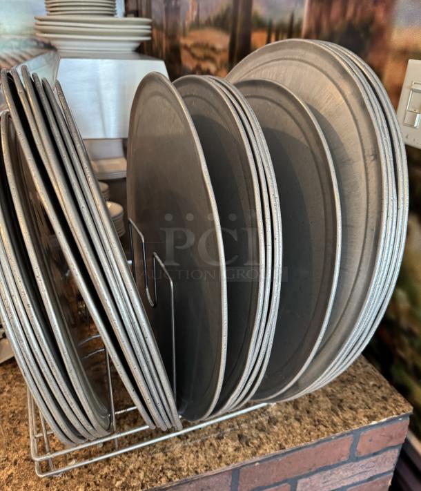 Assorted round pizza pans with a metal rack, showing light wear. Ideal for restaurant or home use.