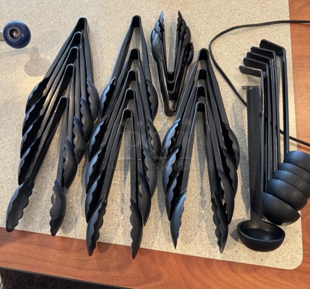 Assorted black plastic tongs and ladles, total 24 pieces, in good condition. Tongs have scalloped edges; ladles are round.