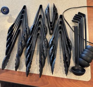 Assorted black plastic tongs and ladles, total 24 pieces, in good condition. Tongs have scalloped edges; ladles are round.