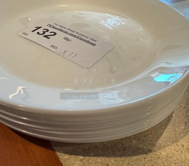 Set of 11 white ceramic dinner plates, 10-inch diameter, in good condition. Visible label with lot number 132 for auction.
