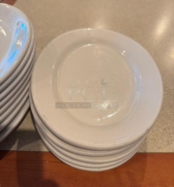 Assorted oval ceramic platters and plates, stacked, varying sizes, white, glossy finish, slight wear visible. Auction set of 17.