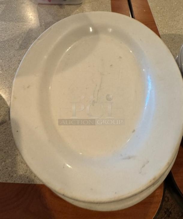 Assorted oval ceramic platters and plates, showing wear and marks; variety of sizes, ideal for collector or decor use.