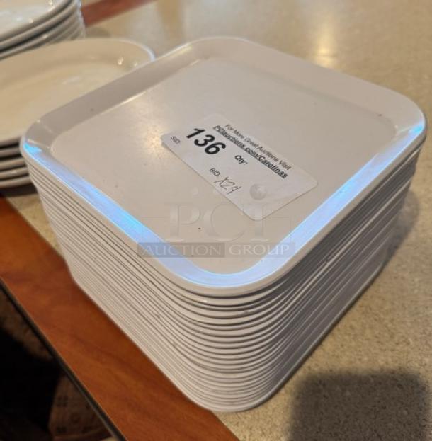 Square white ceramic plates, stack of 24, glossy finish, label shows item number 136, suitable for serving or display.