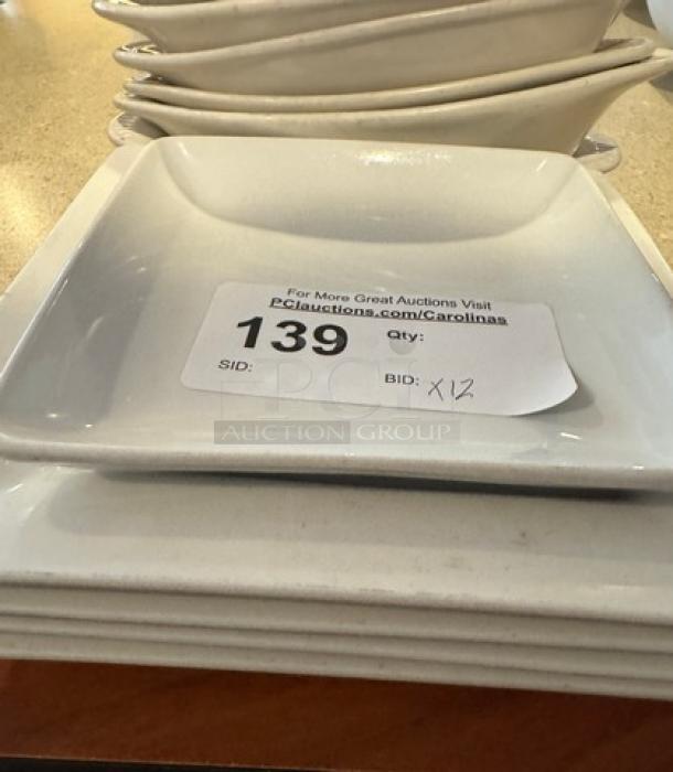 Assorted white ceramic plates, including square and oval dishes, 12 pieces. Visible auction tag with "139" and "Qty: 12."