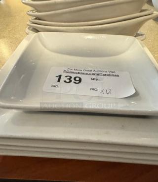 Assorted white ceramic plates, including square and oval dishes, 12 pieces. Visible auction tag with "139" and "Qty: 12."