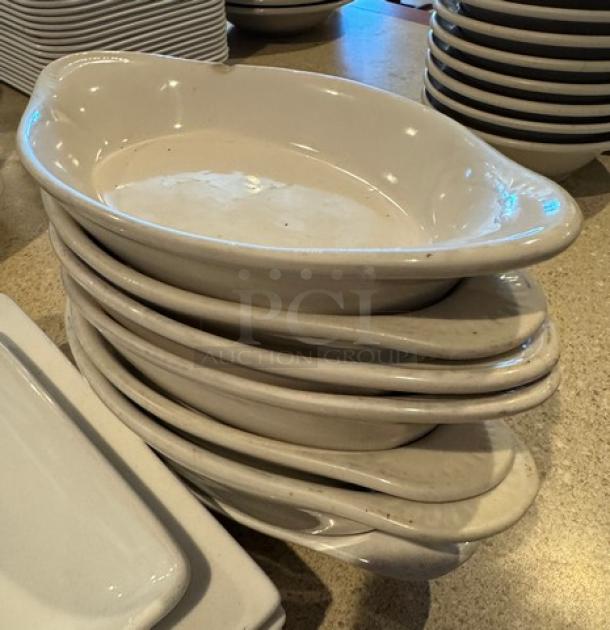 Assorted white ceramic plates; includes stacked square and oval dishes. Smooth finish, lightly used condition, 12 pieces.