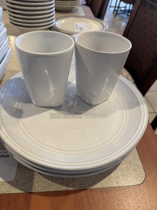 Assorted white ceramic deep bowls, plates, and cups set; 14 items; includes two cups on plates; good condition.