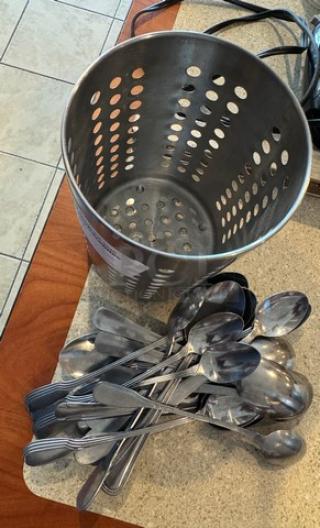 Metal utensil holder with perforated sides, containing assorted stainless steel spoons.