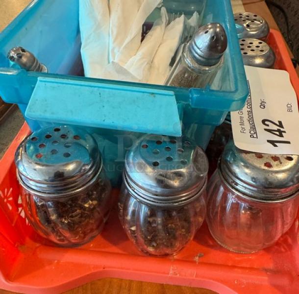 Assorted shakers with metal tops and a container of flatware on a tray. Auction tag visible. Good condition.