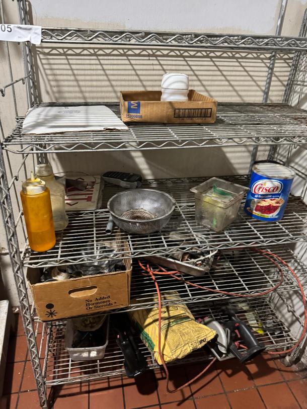 Wire floor rack with 5 shelves, metal construction. Visible wear. Contains various items like boxes, bottles, and tools.