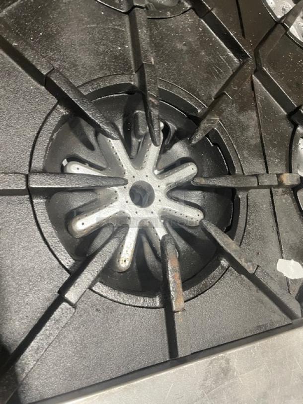Garland H284 commercial range burner with cast iron grate, natural gas, showing wear. Stainless steel surface visible.