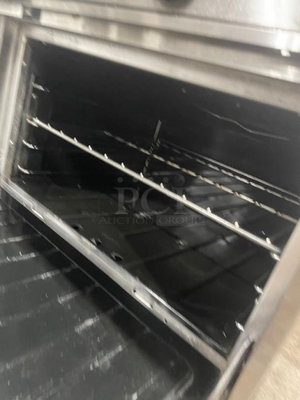 Garland H284 stainless steel 10-burner range and double oven with wired rack, overhead salamander shelf, and backsplash.