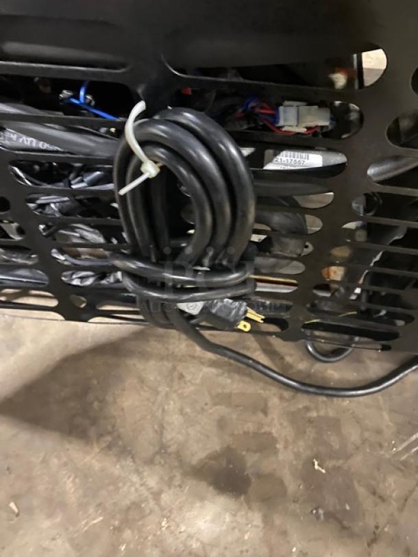 Structural Concepts B42 refrigerated display case wiring and power plug, showing coiled cables and vented back panel.