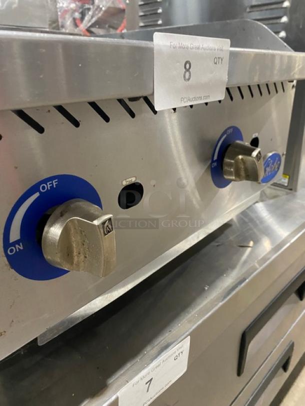 Globe stainless steel natural gas countertop charbroiler with control knobs, serial number 1715042736, on legs.