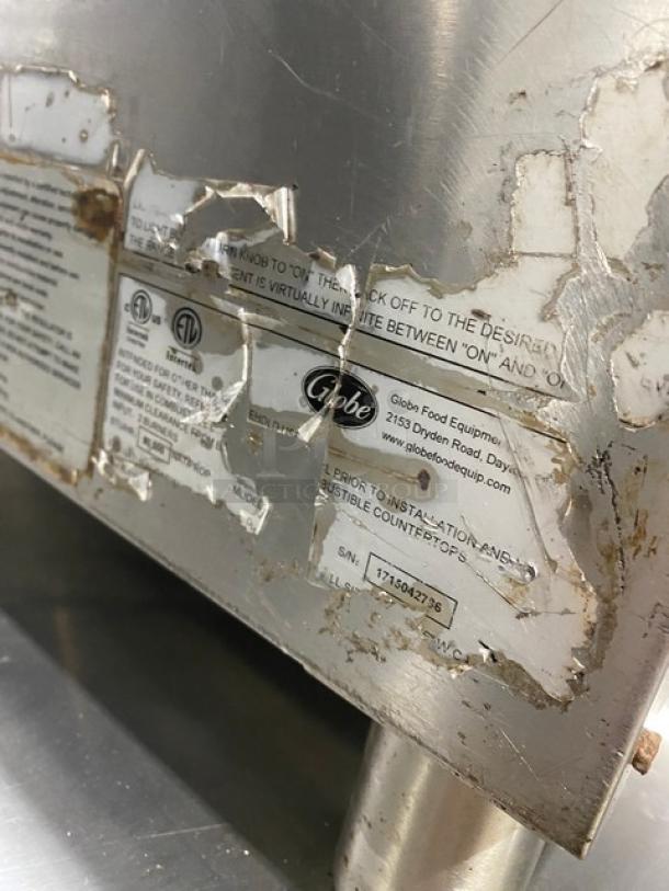 Globe commercial stainless steel natural gas countertop char broiler, model features worn labels, SN: 1715042736, on legs.